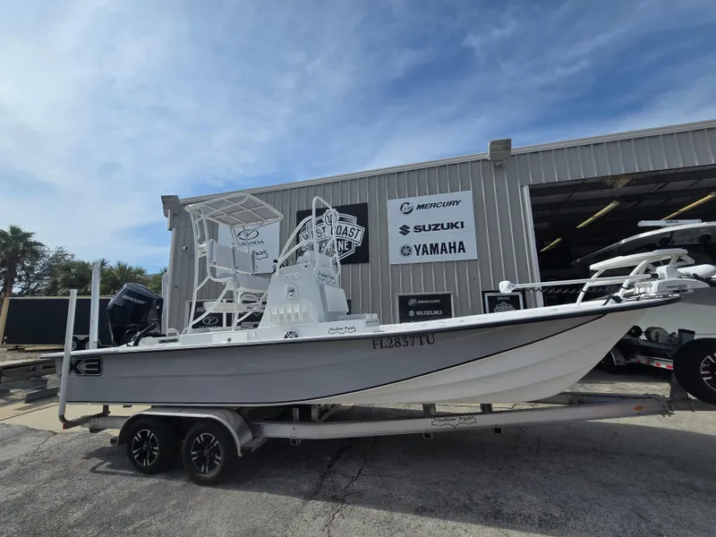 Slide: The Image of 2024 Shallow Sport X3 boat on trailer outside dealership with Suzuki and Yamaha signage. - 2