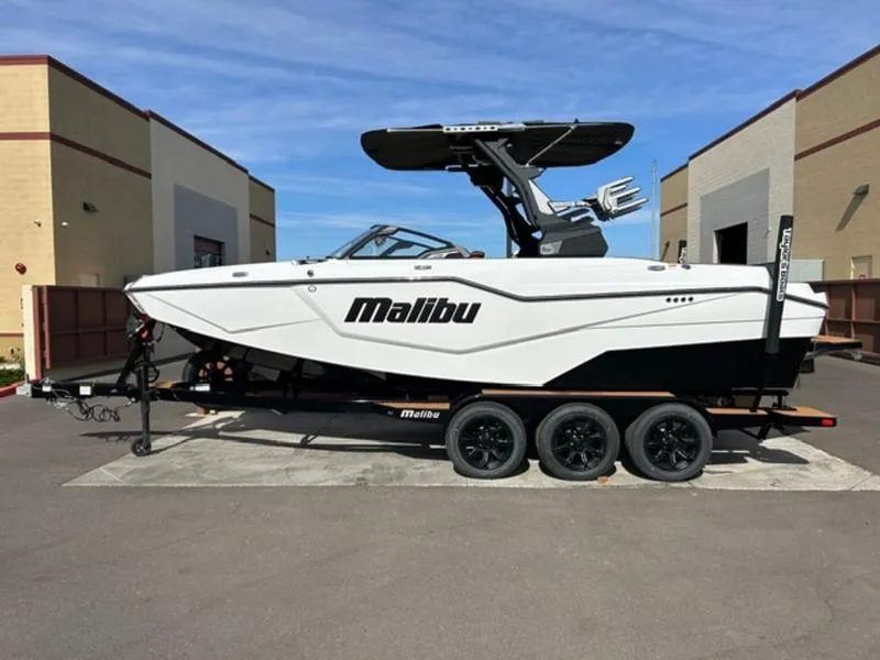 Slide: The Image of 2025 Malibu M230 boat on trailer, parked outdoors, side view. - 1