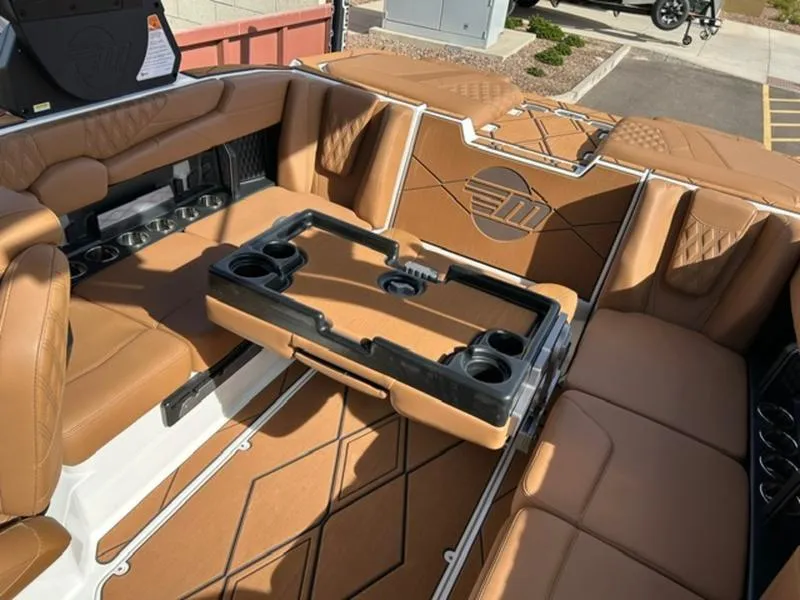 Slide: The Image of 2025 Malibu M230 boat interior with tan leather seating and a central table. - 22