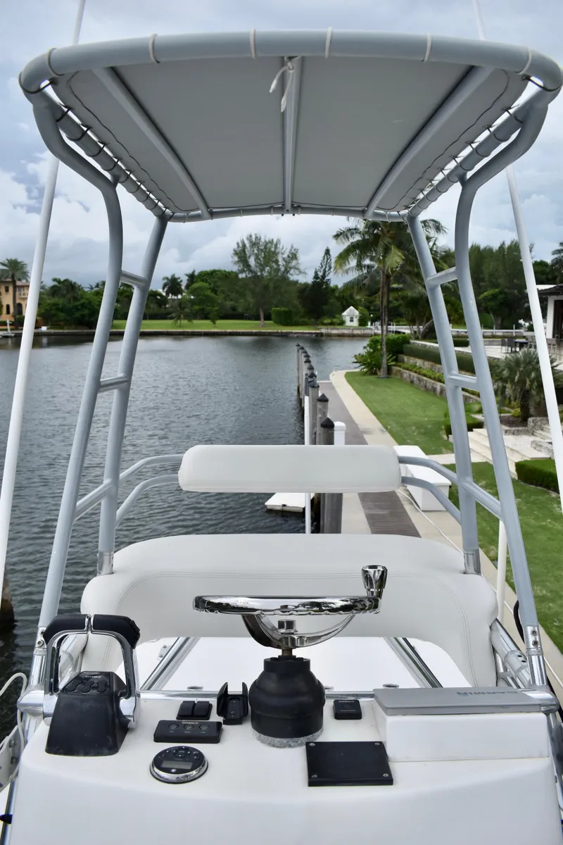 Slide: The Image of 2013 Invincible 42 Open Fisherman boat helm with canopy, docked by a scenic waterfront. - 29