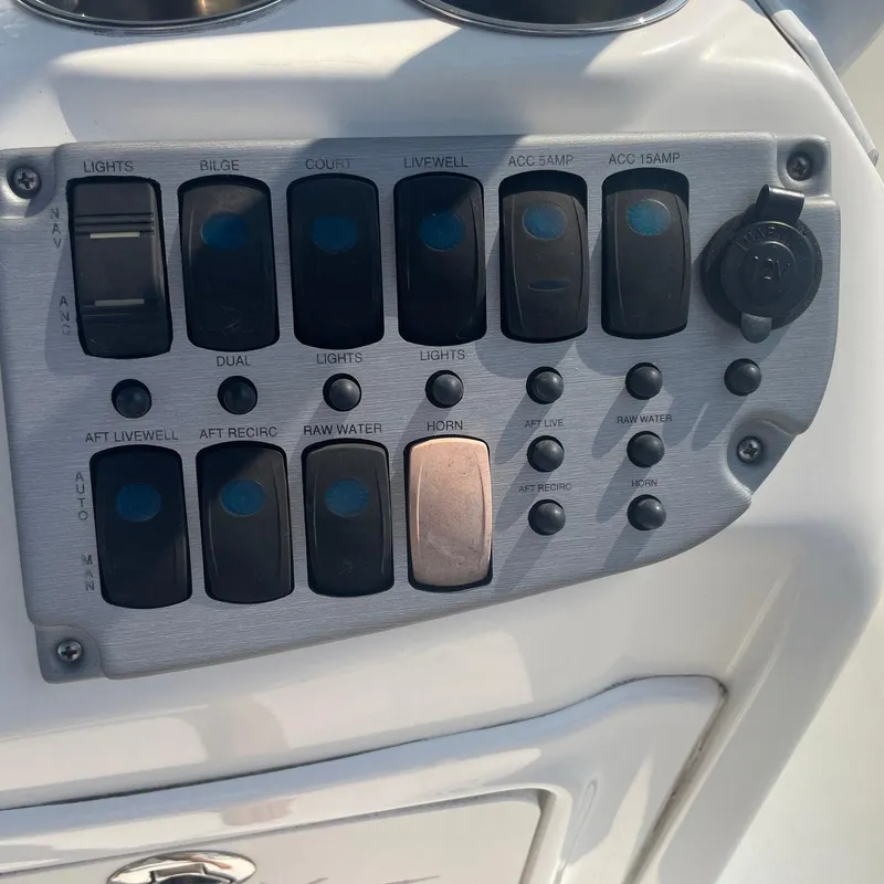 Slide: The Image of Control panel of a 2015 NauticStar 2200XS Offshore boat with various switches. - 16