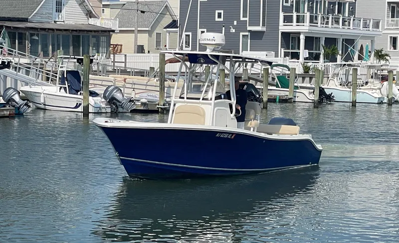 Slide: The Image of 2015 NauticStar 2200XS Offshore boat in marina, surrounded by docks and waterfront homes. - 2