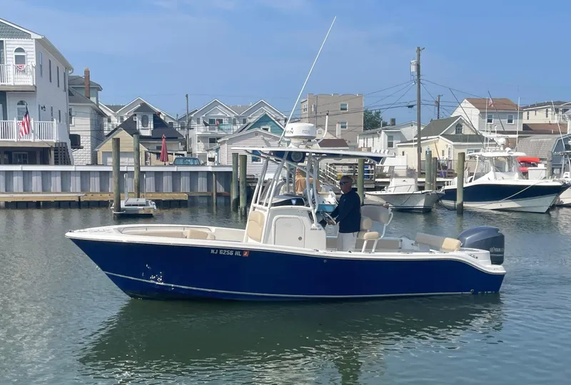 Slide: The Image of 2015 NauticStar 2200XS Offshore boat on water near residential docks. - 3