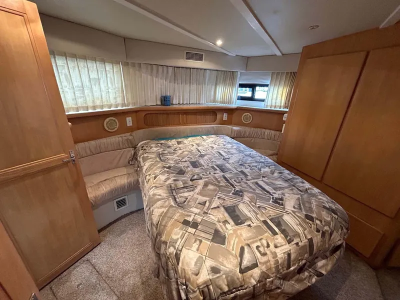 Slide: The Image of 1995 Carver 370 Aft Cabin bedroom with patterned bedspread and wood paneling. - 11