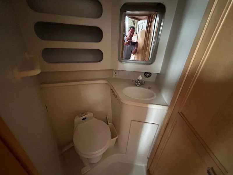 Slide: The Image of 1995 Carver 370 Aft Cabin bathroom with toilet, sink, and mirror. - 12