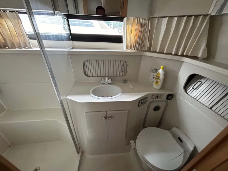 Slide: The Image of 1995 Carver 370 Aft Cabin bathroom with sink, toilet, and shower, featuring natural light. - 13