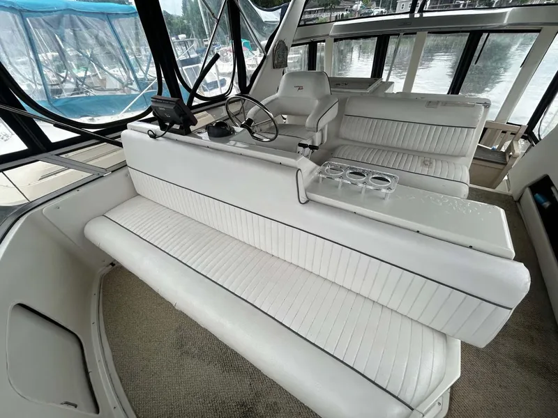 Slide: The Image of 1995 Carver 370 Aft Cabin interior with white seating and helm, docked by the water. - 19