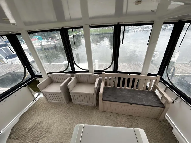 Slide: The Image of 1995 Carver 370 Aft Cabin interior with seating, overlooking marina through large windows. - 21