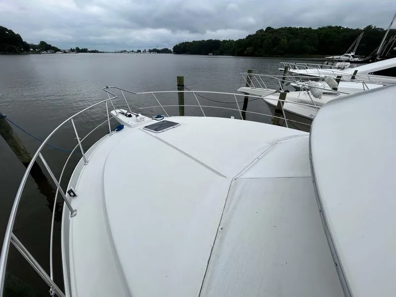Slide: The Image of 1995 Carver 370 Aft Cabin yacht docked on a calm lake under cloudy skies. - 29