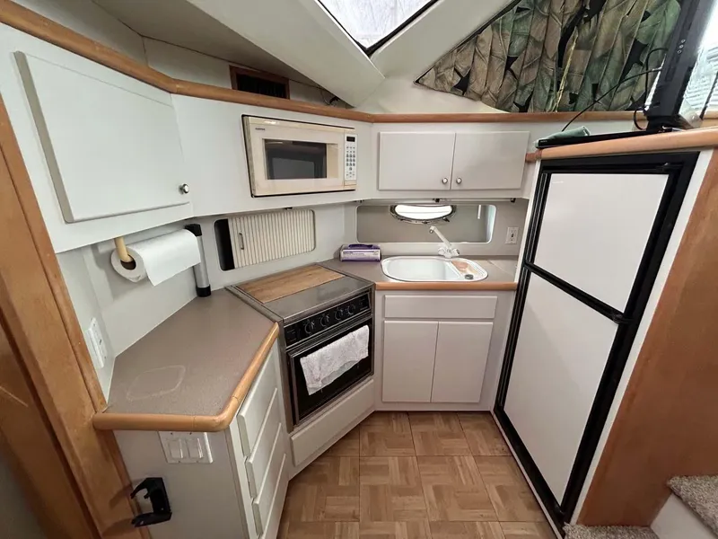 Slide: The Image of 1995 Carver 370 Aft Cabin kitchen with microwave, stove, sink, and refrigerator. - 8