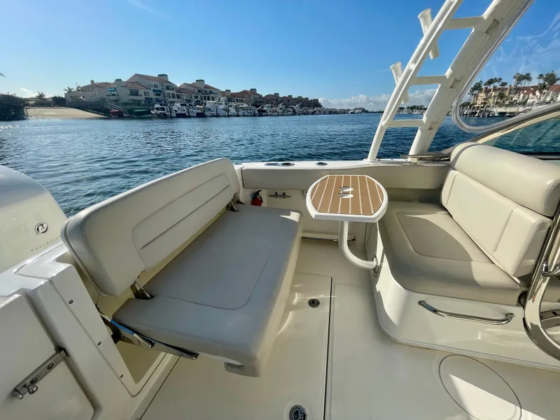 Slide: The Image of 2018 Boston Whaler 230 Vantage boat interior with seating and table, overlooking a marina. - 14