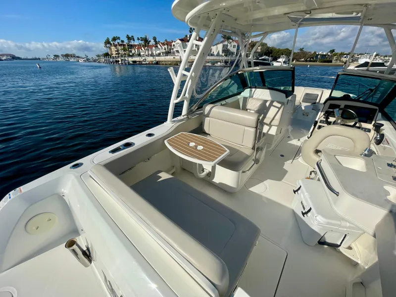 Slide: The Image of 2018 Boston Whaler 230 Vantage boat interior with seating and table, docked by waterfront homes. - 18