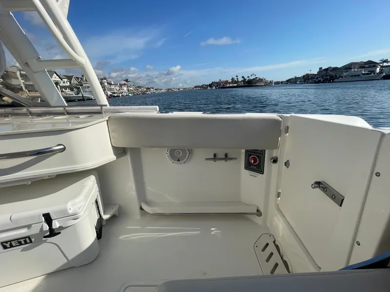 Slide: The Image of 2018 Boston Whaler 230 Vantage boat interior with Yeti cooler, docked by waterfront homes. - 22