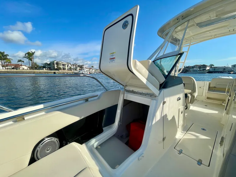 Slide: The Image of 2018 Boston Whaler 230 Vantage boat interior with open storage compartment, docked by waterfront. - 27