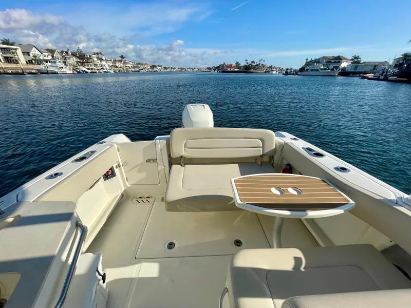 Slide: The Image of 2018 Boston Whaler 230 Vantage boat interior with seating and table on calm water. - 33