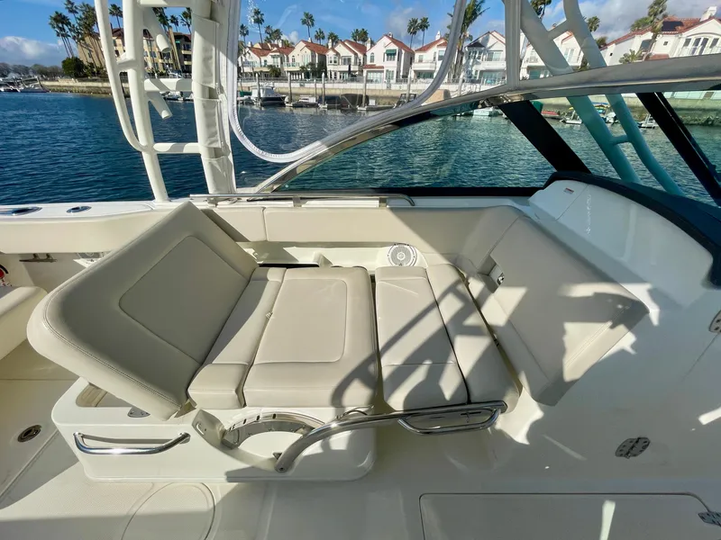 Slide: The Image of 2018 Boston Whaler 230 Vantage boat interior with beige seating, docked near waterfront homes. - 44