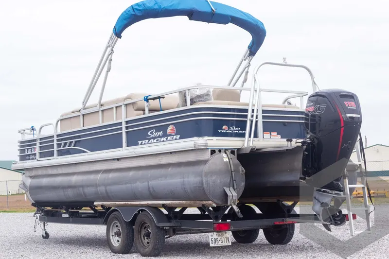 Slide: The Image of 2020 Sun Tracker Fishin' Barge 22 DLX pontoon boat on trailer, blue canopy. - 18