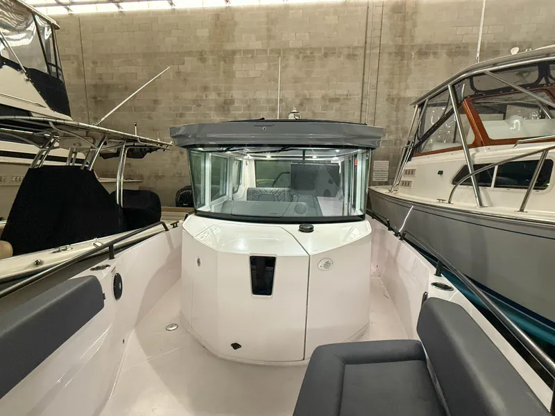 Slide: The Image of 2021 Axopar 28 CABIN boat in a storage facility, surrounded by other vessels. - 13