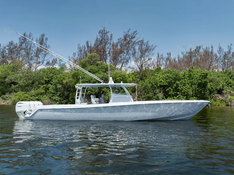 Slide: The Image of 2025 Contender 44 ST boat on calm water, surrounded by lush greenery. - 1