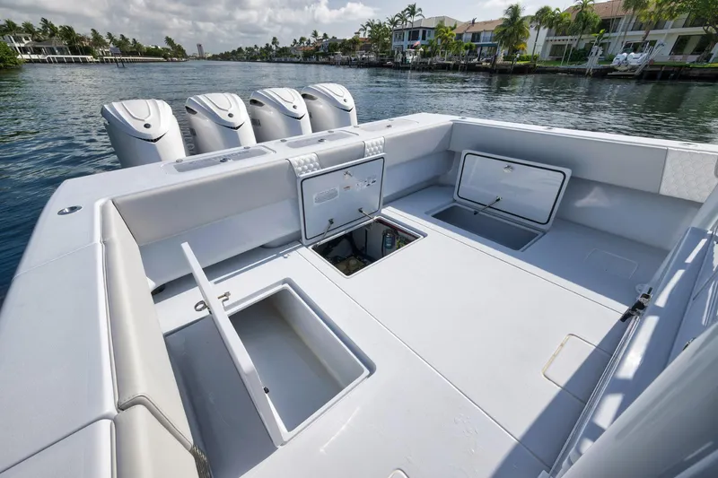 Slide: The Image of 2025 Contender 44 ST boat with open storage compartments and four outboard engines on a calm waterway. - 38
