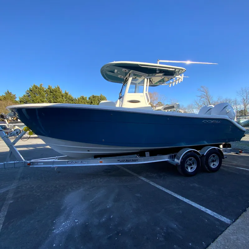 Slide: The Image of 2025 Cobia 240 Center Console boat on trailer, parked outdoors under clear blue sky. - 6