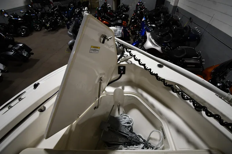Slide: The Image of 2022 Boston Whaler 250 Dauntless boat storage compartment with rope, surrounded by motorcycles. - 11