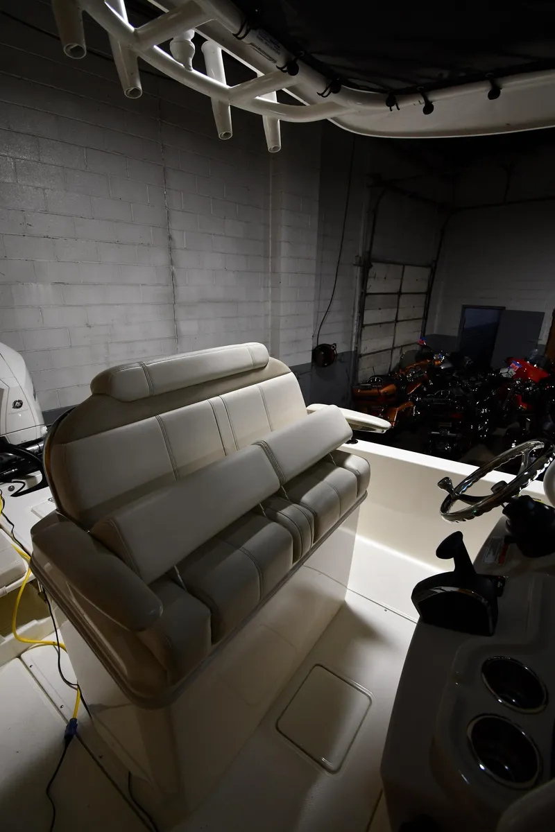 Slide: The Image of 2022 Boston Whaler 250 Dauntless boat interior with seating and controls in a dimly lit garage. - 21
