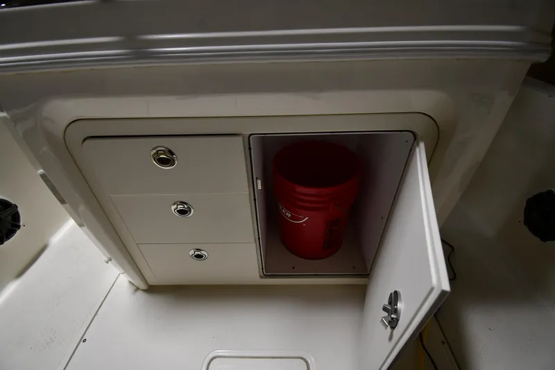 Slide: The Image of 2022 Boston Whaler 250 Dauntless storage compartment with red bucket inside. - 28