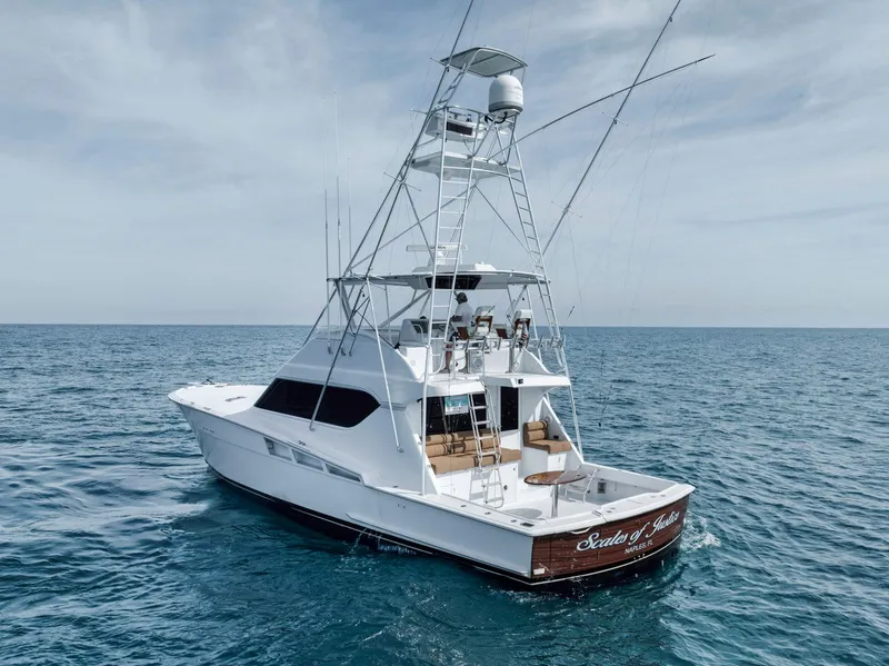 Slide: The Image of 1999 Hatteras 60 Convertible yacht on open sea, featuring a spacious deck and tower. - 12