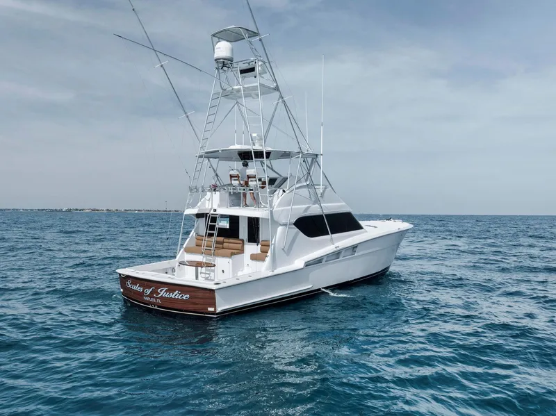 Slide: The Image of 1999 Hatteras 60 Convertible yacht on open sea, featuring a sleek design and fishing tower. - 13