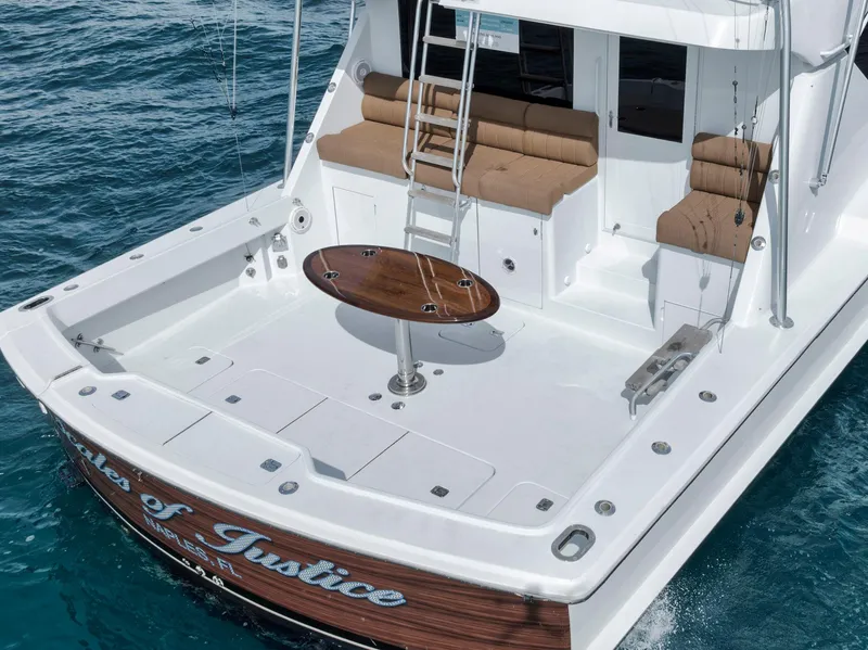 Slide: The Image of 1999 Hatteras 60 Convertible yacht with spacious deck and seating on blue ocean water. - 18