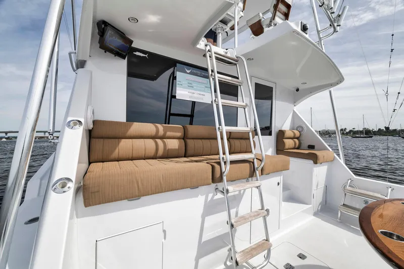 Slide: The Image of 1999 Hatteras 60 Convertible yacht with cushioned seating and ladder on deck. - 19