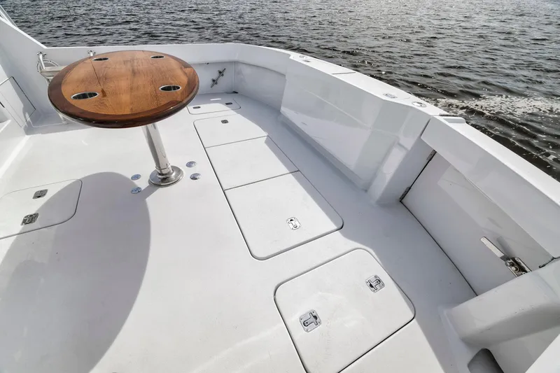 Slide: The Image of 1999 Hatteras 60 Convertible yacht deck with wooden table, overlooking calm waters. - 22