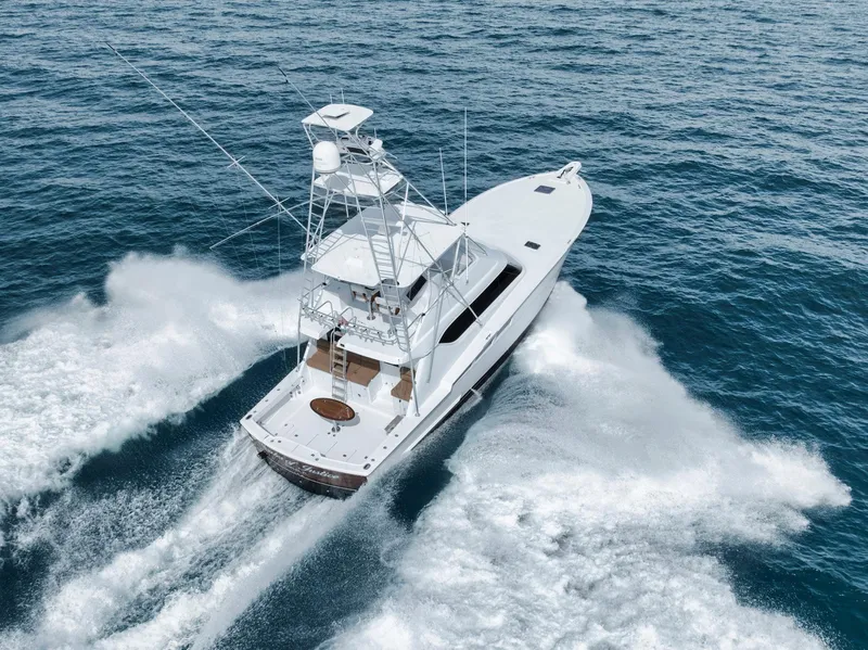 Slide: The Image of 1999 Hatteras 60 Convertible yacht cruising on open sea, creating dynamic water trails. - 4