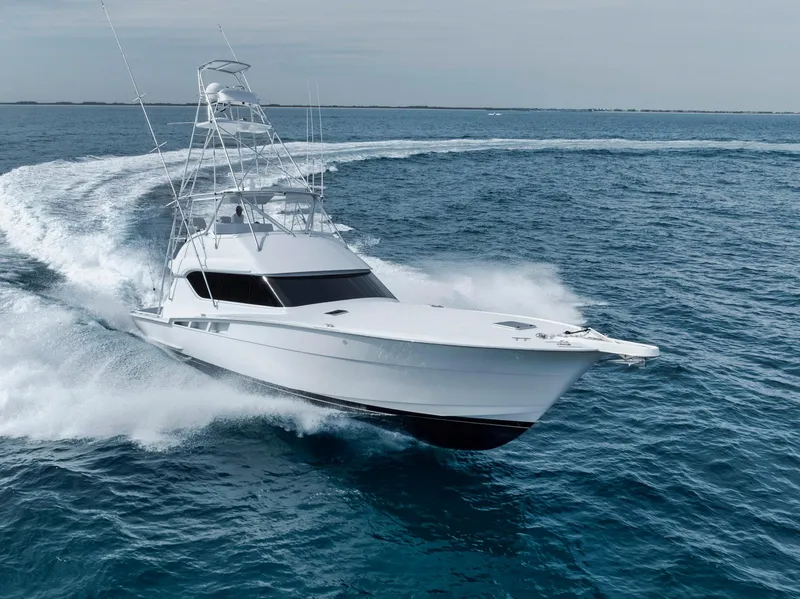 Slide: The Image of 1999 Hatteras 60 Convertible yacht cruising swiftly on open ocean waters. - 8