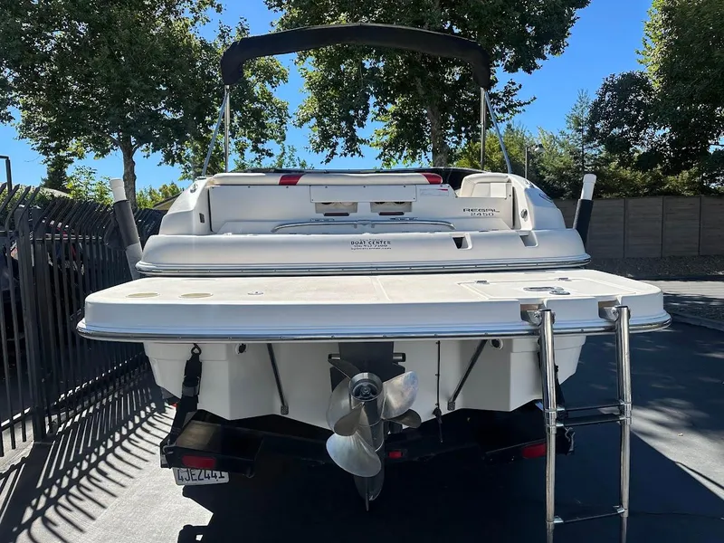 Slide: The Image of 2006 Regal 2450 Cuddy boat, rear view with propeller and ladder, parked outdoors. - 10