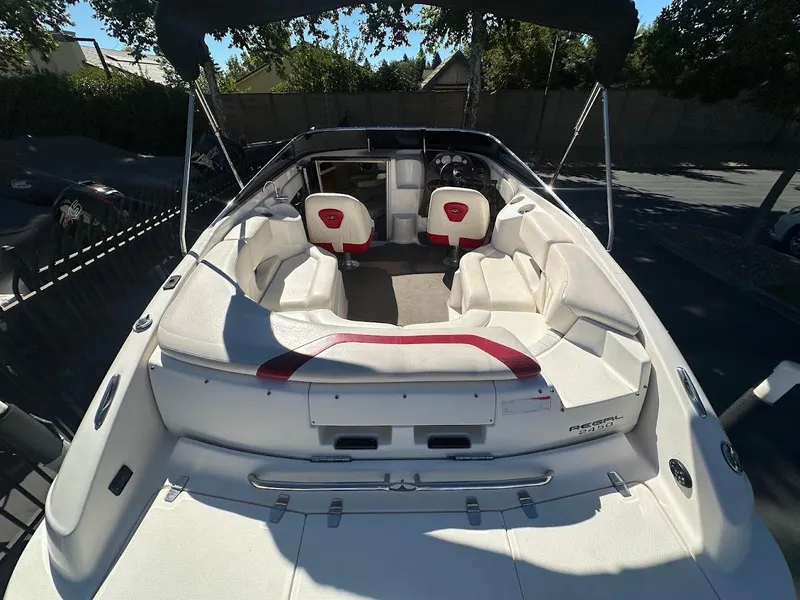 Slide: The Image of 2006 Regal 2450 Cuddy boat with white seating and red accents, docked outdoors. - 14