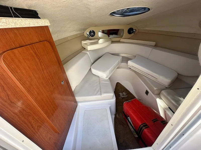 Slide: The Image of 2006 Regal 2450 Cuddy cabin interior with white seating and wooden door. - 28
