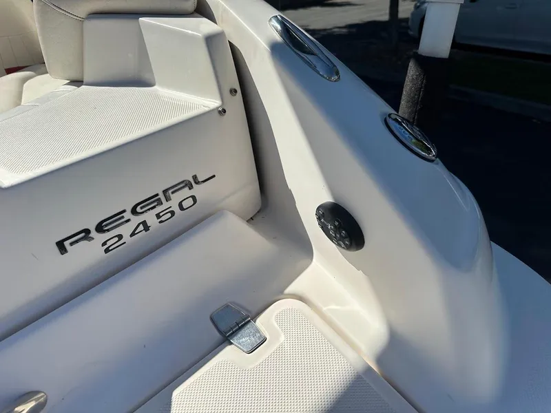 Slide: The Image of 2006 Regal 2450 Cuddy boat, white interior, close-up view of seating and branding. - 33