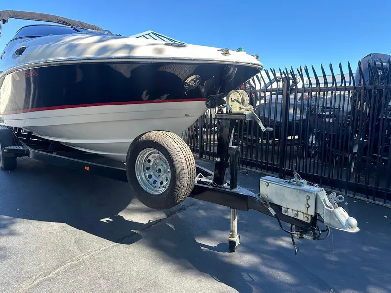 Slide: The Image of 2006 Regal 2450 Cuddy boat on trailer, parked near black metal fence. - 6