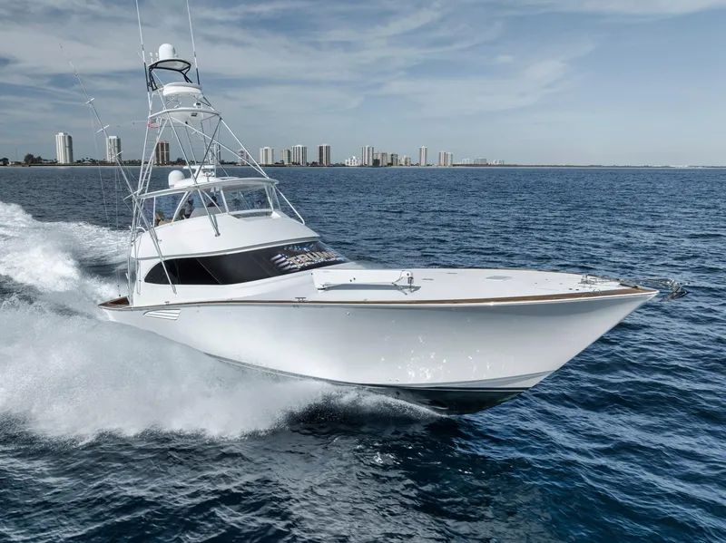 Slide: The Image of 2015 Viking 70 Convertible yacht cruising on open water with city skyline in background. - 8