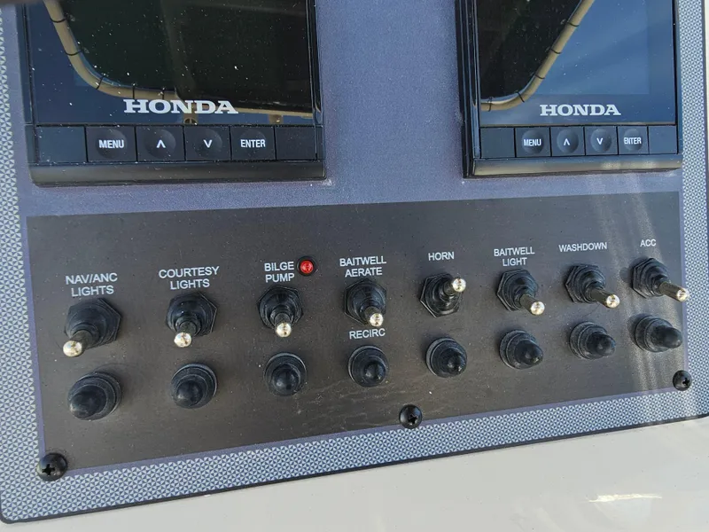 Slide: The Image of Control panel of 2024 Scout Honda Seabrook 195 CF boat with switches and displays. - 16