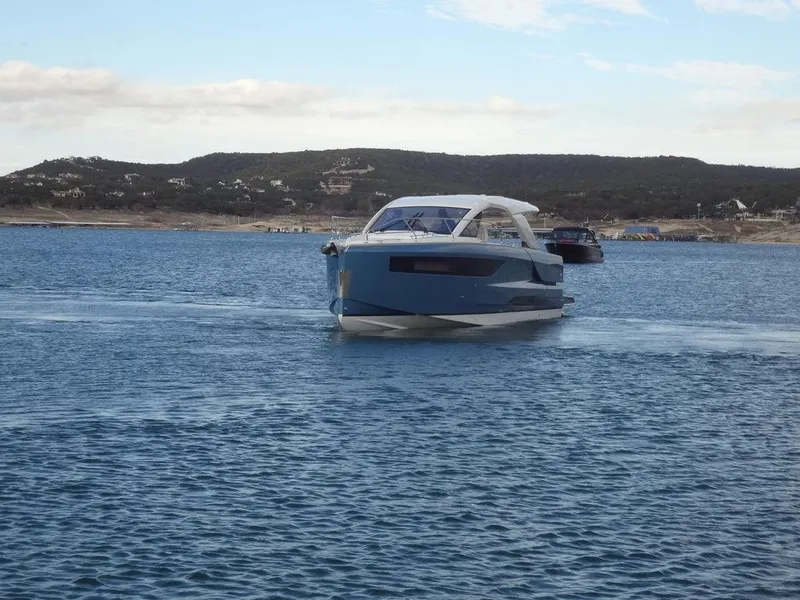 Slide: The Image of 2025 Jeanneau DB/43 OB yacht cruising on a calm sea with hills in the background. - 17