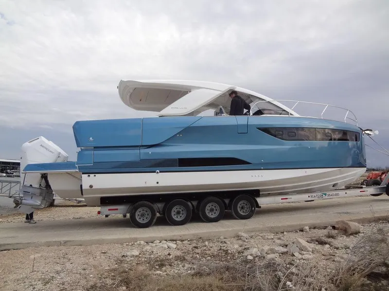 Slide: The Image of 2025 Jeanneau DB/43 OB boat on trailer, blue and white design, parked outdoors. - 19
