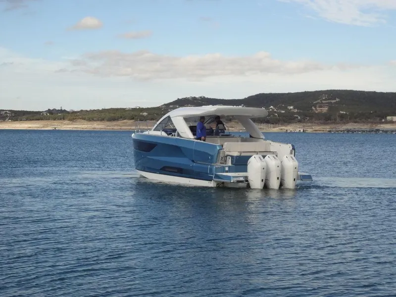 Slide: The Image of 2025 Jeanneau DB/43 OB boat cruising on calm waters with scenic background. - 6