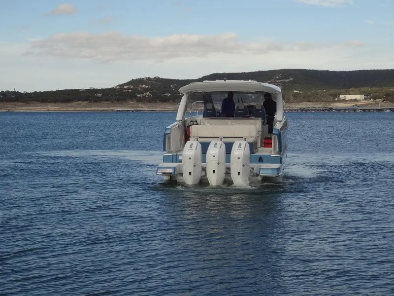 Slide: The Image of 2025 Jeanneau DB/43 OB boat with triple outboard motors on a calm lake. - 7