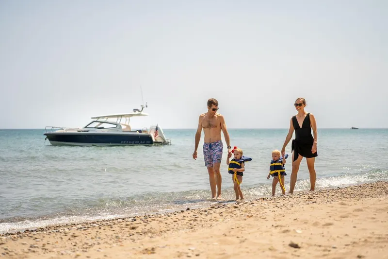 Slide: The Image of Family enjoying beach with Nimbus Weekender 9 boat in the background, 2025 model. - 19