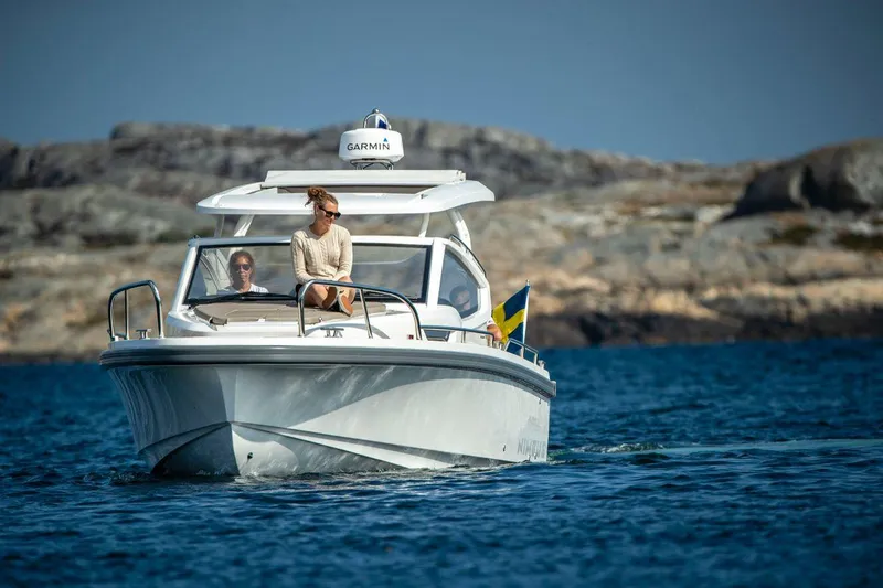 Slide: The Image of 2025 Nimbus Weekender 9 boat cruising on blue water near rocky shoreline. - 24