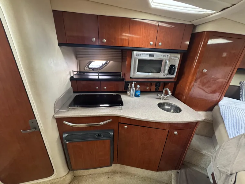 Slide: The Image of 2007 Sea Ray 310 yacht kitchen with wood cabinets, microwave, and compact sink. - 24