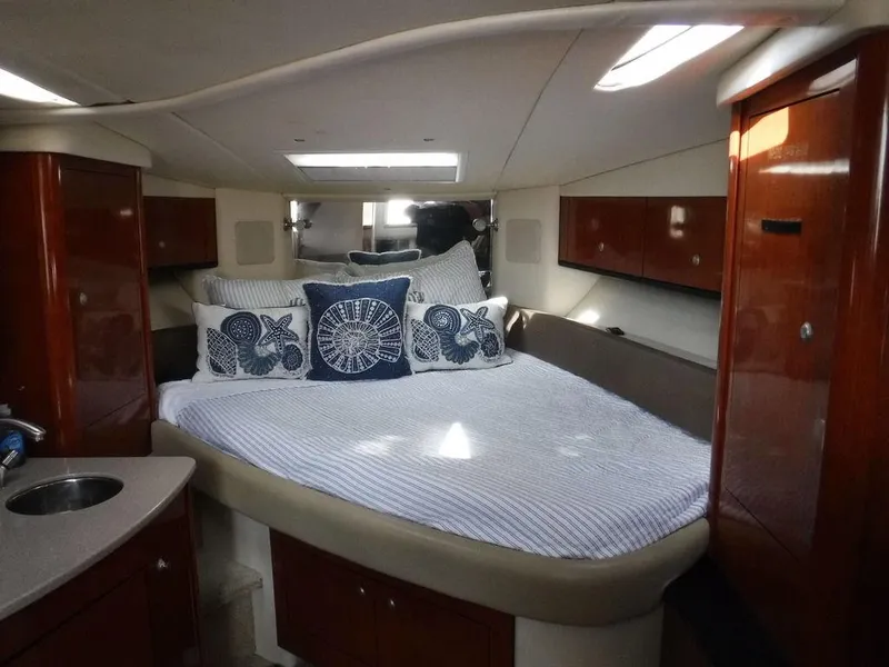 Slide: The Image of 2007 Sea Ray 310 cabin interior with bed, pillows, and wooden cabinetry. - 5